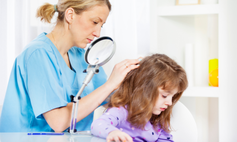 ممرضة مدرسة أمريكية تفحص شعر طالبة للكشف عن القمل داخل العيادة المدرسية.