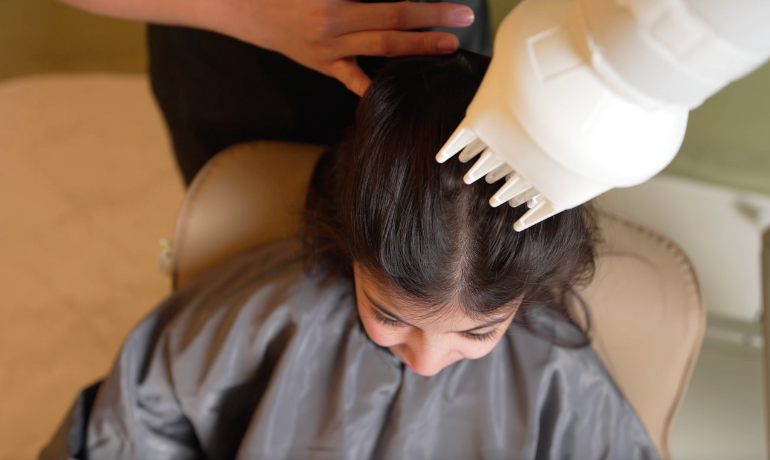 أخصائية تستخدم جهازًا طبيًا آمنًا لإزالة القمل والصيبان من شعر طفلة في جلسة واحدة