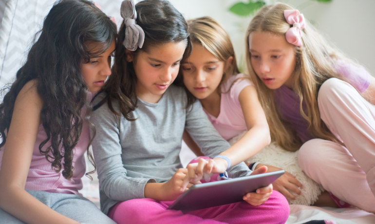 أطفال يجلسون متقاربين حول الآيباد مما يزيد من احتمالية انتقال القمل بسبب تلامس الرؤوس والذي يعتبر اهم أسباب الانتشار الحديث للقمل