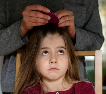 أم تفحص شعر طفلتها للتأكد من وجود القمل للإجابة عن السؤال كيف أعرف أن طفلي مصاب بالقمل