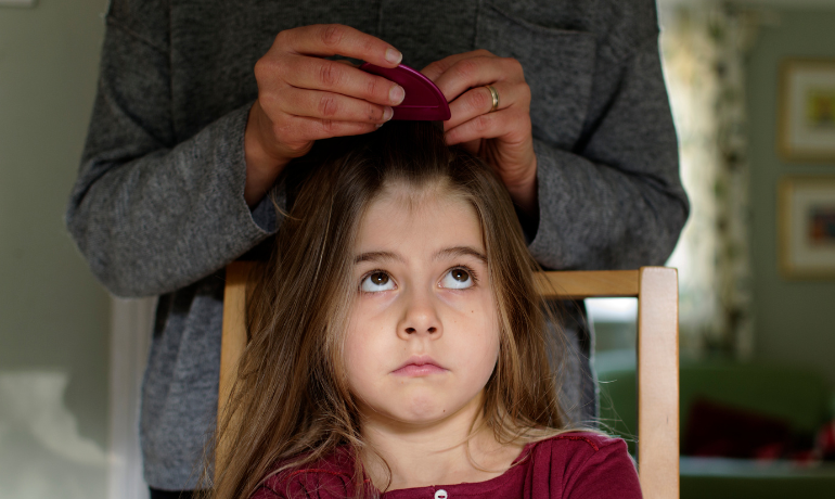 أم تفحص شعر طفلتها للتأكد من وجود القمل للإجابة عن السؤال كيف أعرف أن طفلي مصاب بالقمل